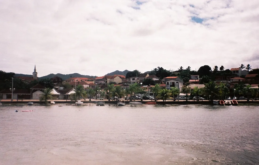 Le bourg des Trois-Îlets en Martinique vu depuis la mer, avec son clocher d'église et ses maisons en bord de baie