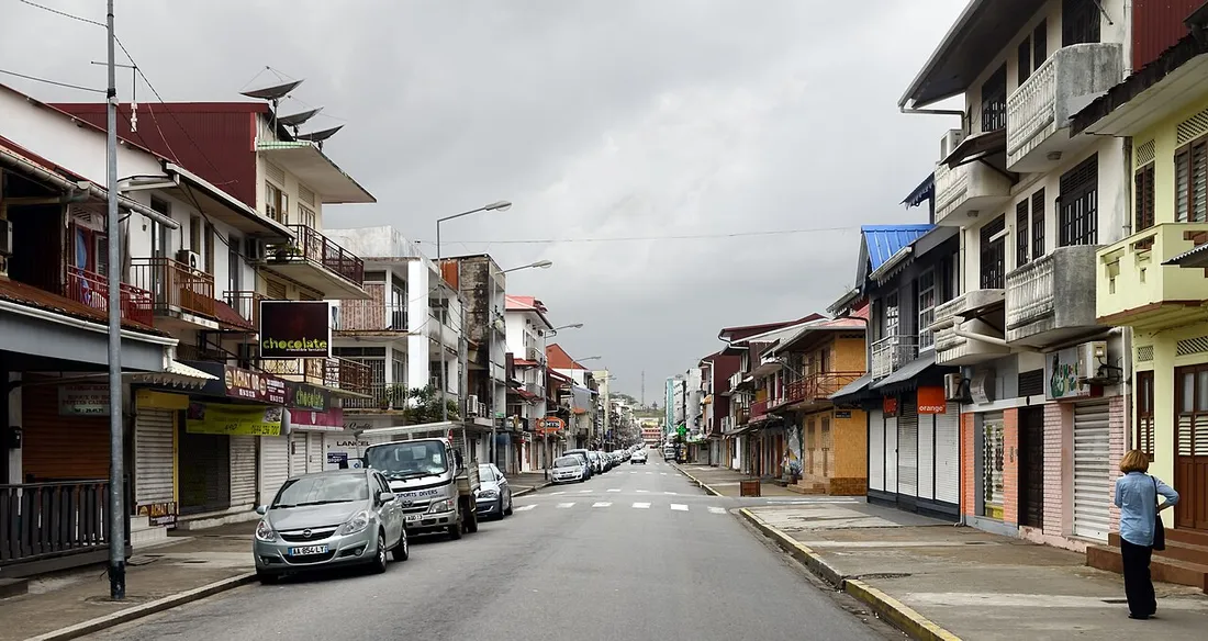 Rue commercante de Cayenne bordee d'immeubles d'habitation avec balcons et commerces, en Guyane