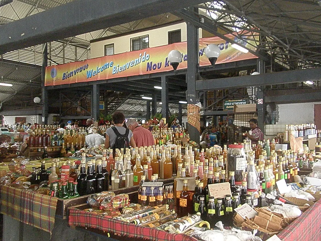 Étal de rhums, sirops et épices sous une bannière de bienvenue en créole au Grand Marché de Fort-de-France, Martinique