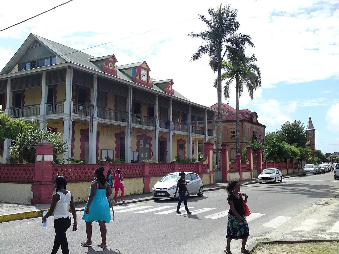 Architecture coloniale en bois du centre historique de Saint-Laurent-du-Maroni en Guyane, avec des passants dans la rue