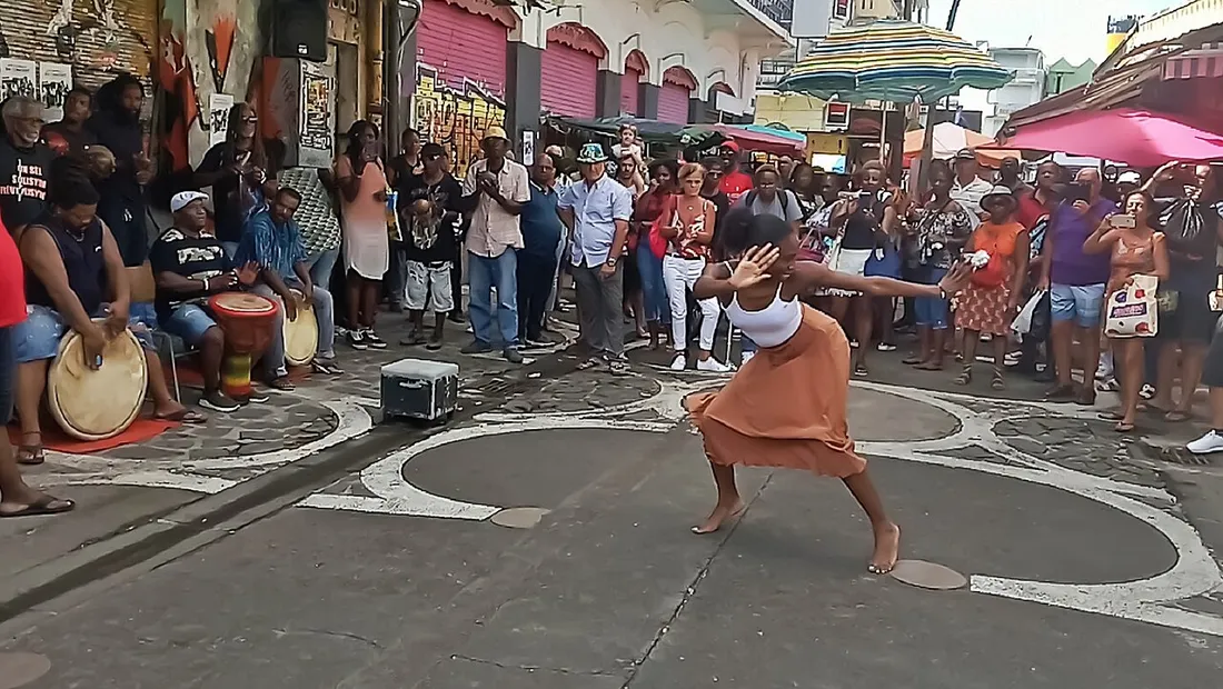 Scene de gwoka en plein air en Guadeloupe : une danseuse de lewoz devant les tambours ka et un public rassemble dans la rue lors d'une fete