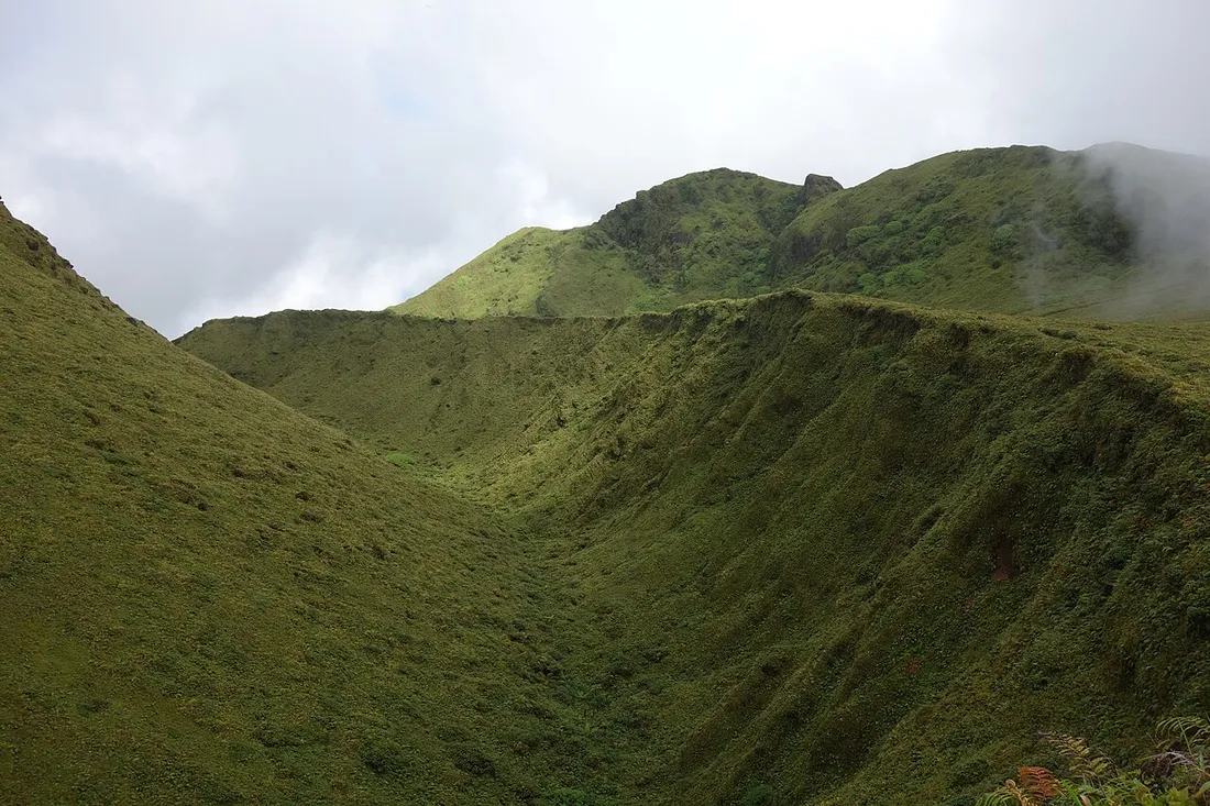 Cratere et domes du sommet de la Montagne Pelee en Martinique, pentes couvertes de vegetation verte sous les nuages