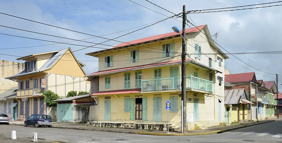 Maison creole traditionnelle a deux etages avec balcon et volets, a l'angle d'une rue de Cayenne en Guyane