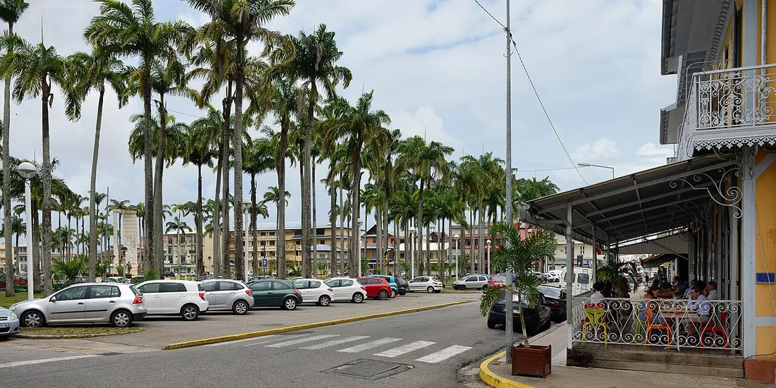 Place des Palmistes à Cayenne bordée de palmiers royaux et d'un bâtiment créole à véranda en fer forgé, au cœur du centre historique