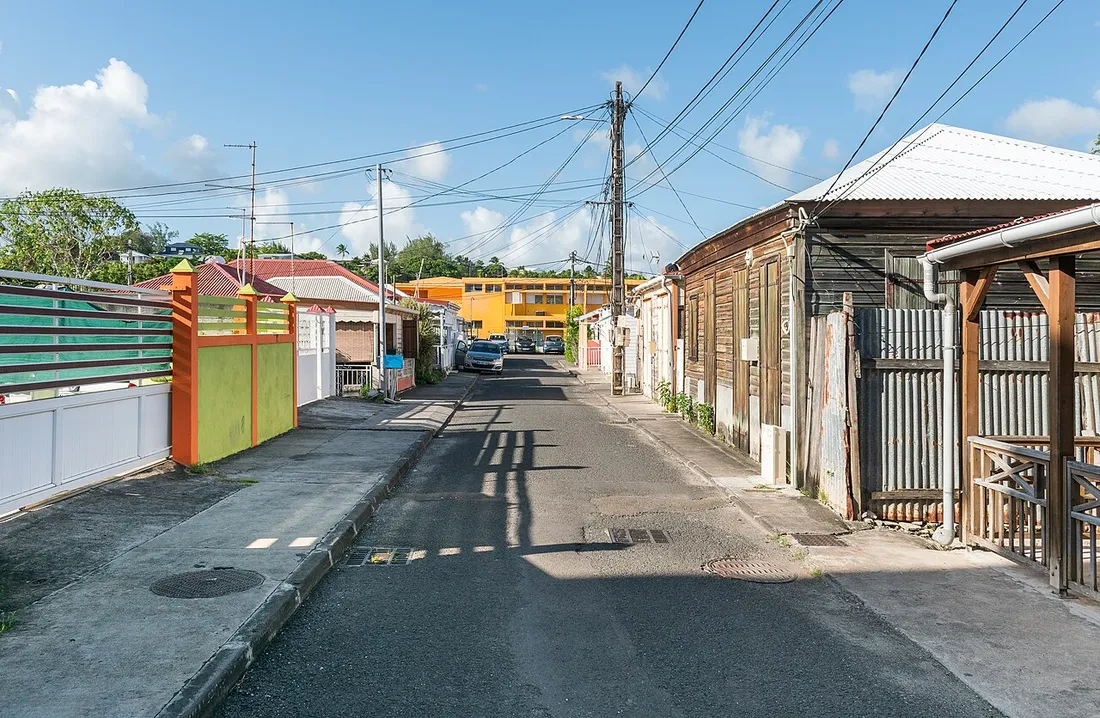 Rue residentielle du bourg de Sainte-Anne en Guadeloupe avec maisons creoles, contexte de la mise en location de meubles de tourisme