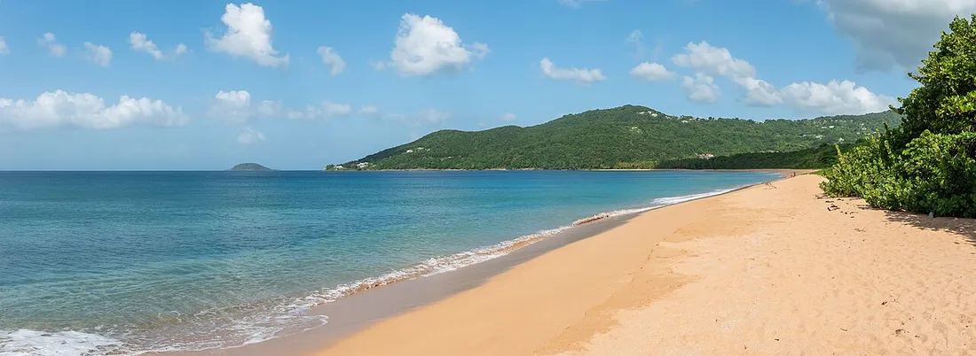 La plage de sable dore de Grande Anse a Deshaies, bordee de collines verdoyantes de la Cote-sous-le-Vent en Guadeloupe