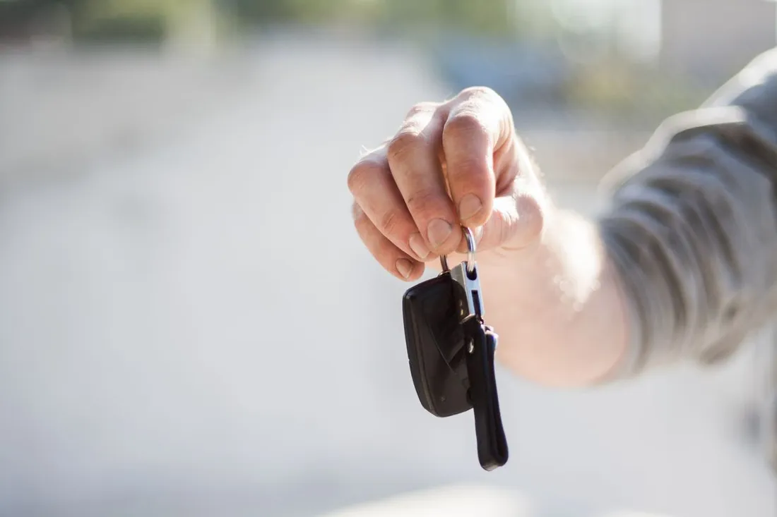 Main tendant les cles d'une voiture, etape de la remise du vehicule lors d'une location