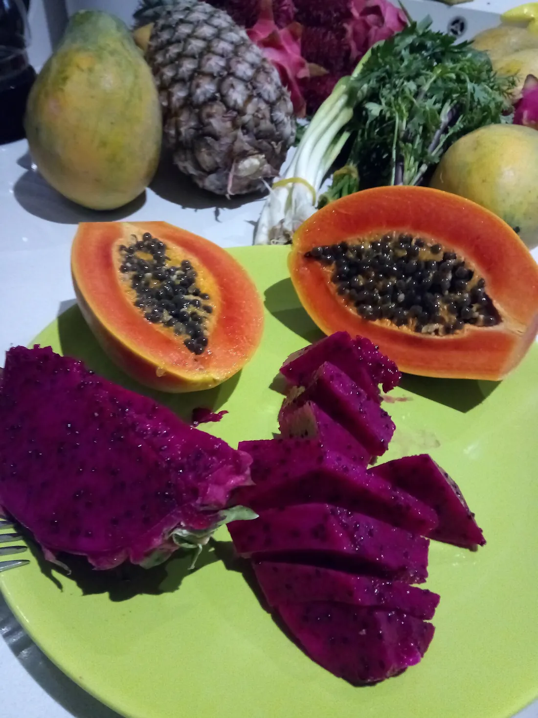 Fruits-pays tropicaux préparés : papaye coupée révélant ses graines noires, ananas, pitaya rouge en tranches et mangues, posés sur une assiette