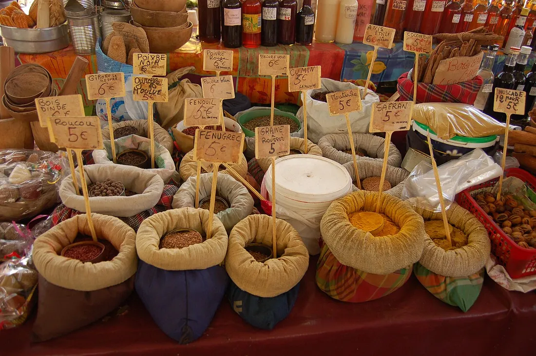 Etal d'epices creoles au marche de Pointe-a-Pitre en Guadeloupe, avec sacs de curry, safran, roucou, fenugrec et poivres et leurs etiquettes de prix