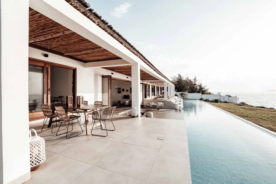 Terrasse et piscine à débordement d'une villa de location en bord de mer sous le soleil des tropiques