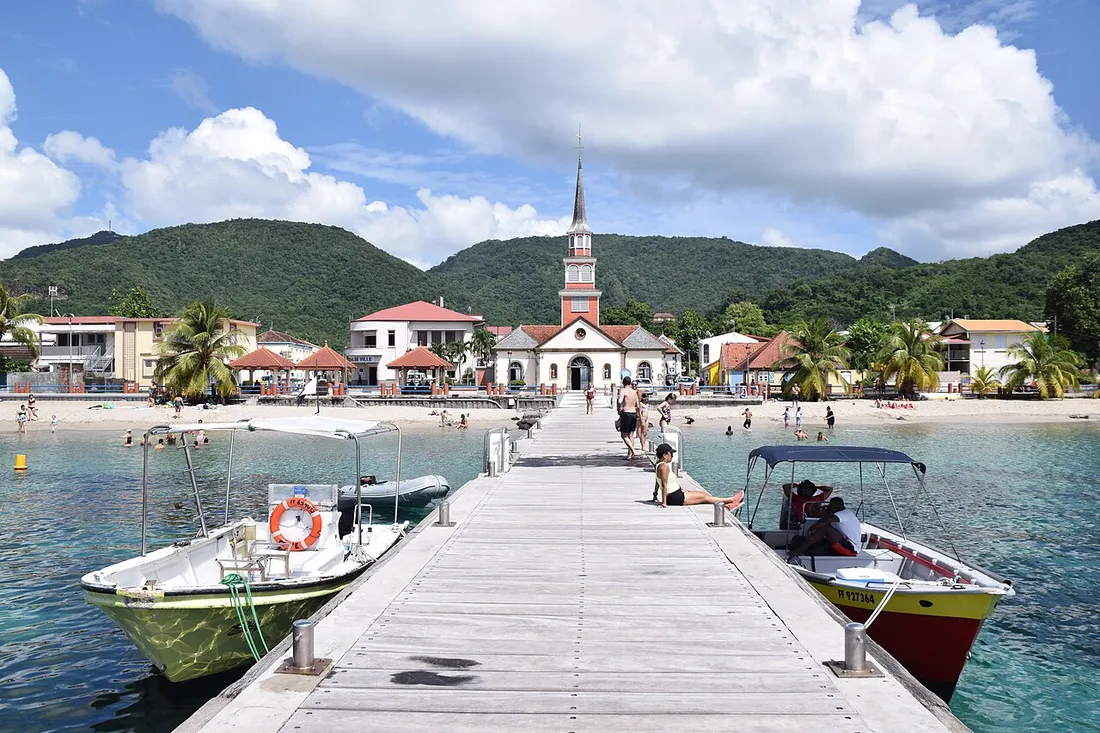 Le bourg des Anses-d'Arlet en Martinique vu depuis le ponton, avec son église, sa plage et ses barques de pêche
