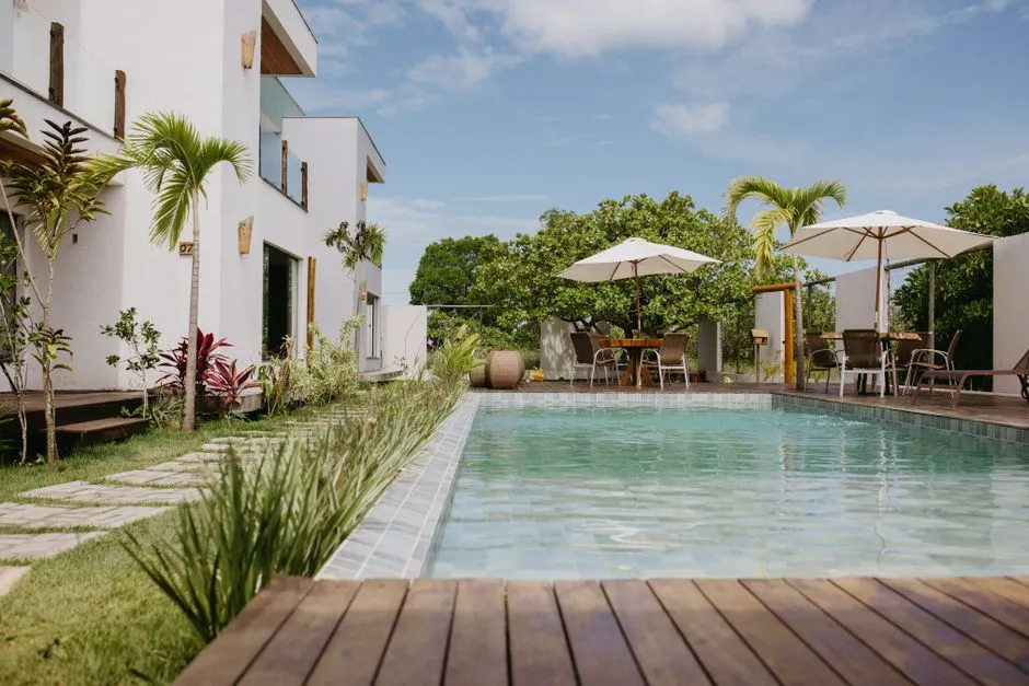 Villa de vacances moderne avec piscine, terrasse en bois et parasols, illustrant un meuble de tourisme aux Antilles
