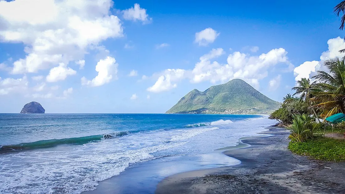 Grande plage de sable du Diamant en Martinique avec vagues poussees par les alizes, le Morne Larcher et le Rocher du Diamant a l'horizon