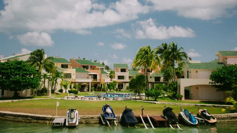 Ensemble de villas de location de vacances identiques bordant une piscine commune sous les palmiers aux Antilles